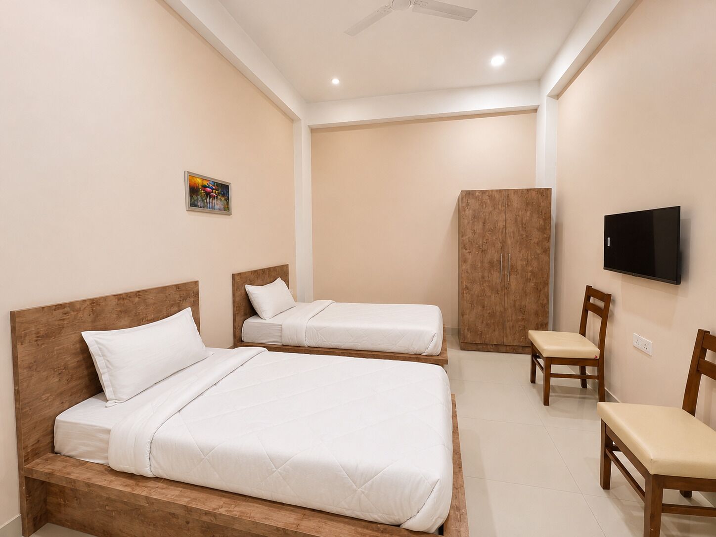 Una habitación de hotel con dos camas, un armario, un televisor y una silla.