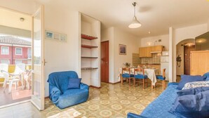 Una sala de estar con sofá, una mesa de comedor con sillas y una zona de cocina con armarios.
