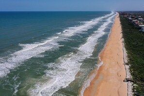 An aerial view of a beach with waves, a sandy shore, and buildings along the coastline. - Beautiful sunsets from 3rd Floor condo #934 (Palm Coast)