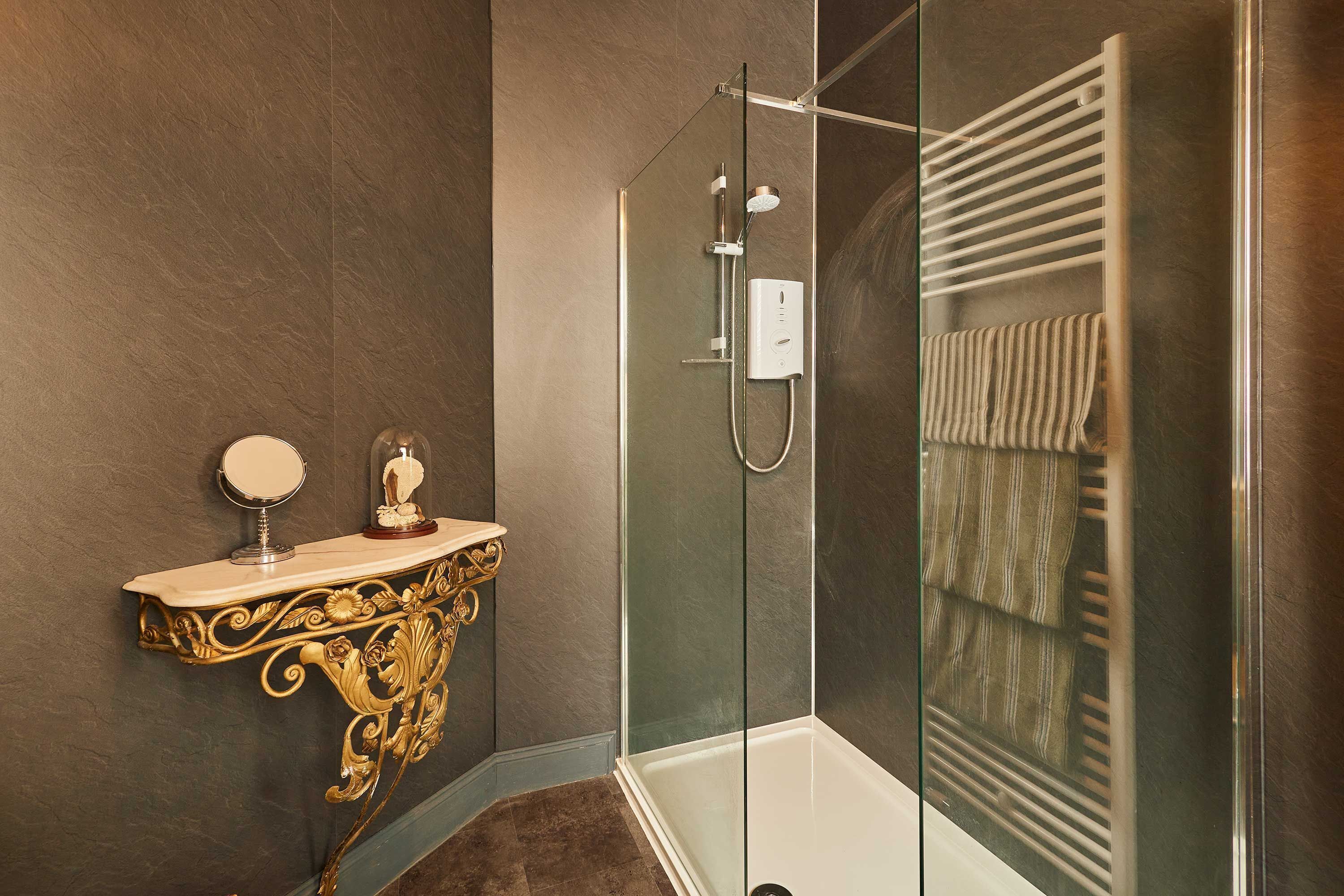 Un baño moderno con cabina de ducha de vidrio, tocador con espejo y perchero.