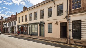 A street view with buildings, a person walking, and a clear sky. - Host Stay - Little Marjorelle (Berwick-upon-Tweed)