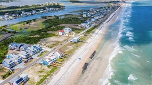 Vista aérea de una zona residencial costera con casas, una playa y un puerto deportivo.
