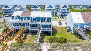 Una propiedad frente a la playa con varias casas azules, terrazas de madera y una playa arenosa.