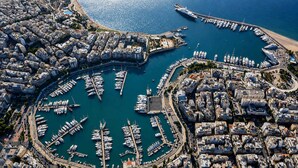 Eine Luftaufnahme eines Yachthafens mit zahlreichen vertäuten Booten, umgeben von dicht bebauten Stadtgebäuden.