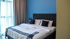 A neatly made bed with white and gray bedding, a dark headboard, and a nightstand with a lamp. - Yogi 1BR Business Bay Gym Pool Parking (Dubai)