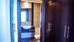 A bathroom with a sink, toilet, and dark wooden cabinets. - Yogi 1BR Business Bay Gym Pool Parking (Dubai)