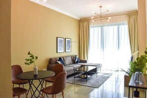 Ein modernes Wohnzimmer mit einer Couch, einem Couchtisch und Sesseln. An der Wand hängen zwei gerahmte Bilder und auf dem Tisch steht eine Pflanze.