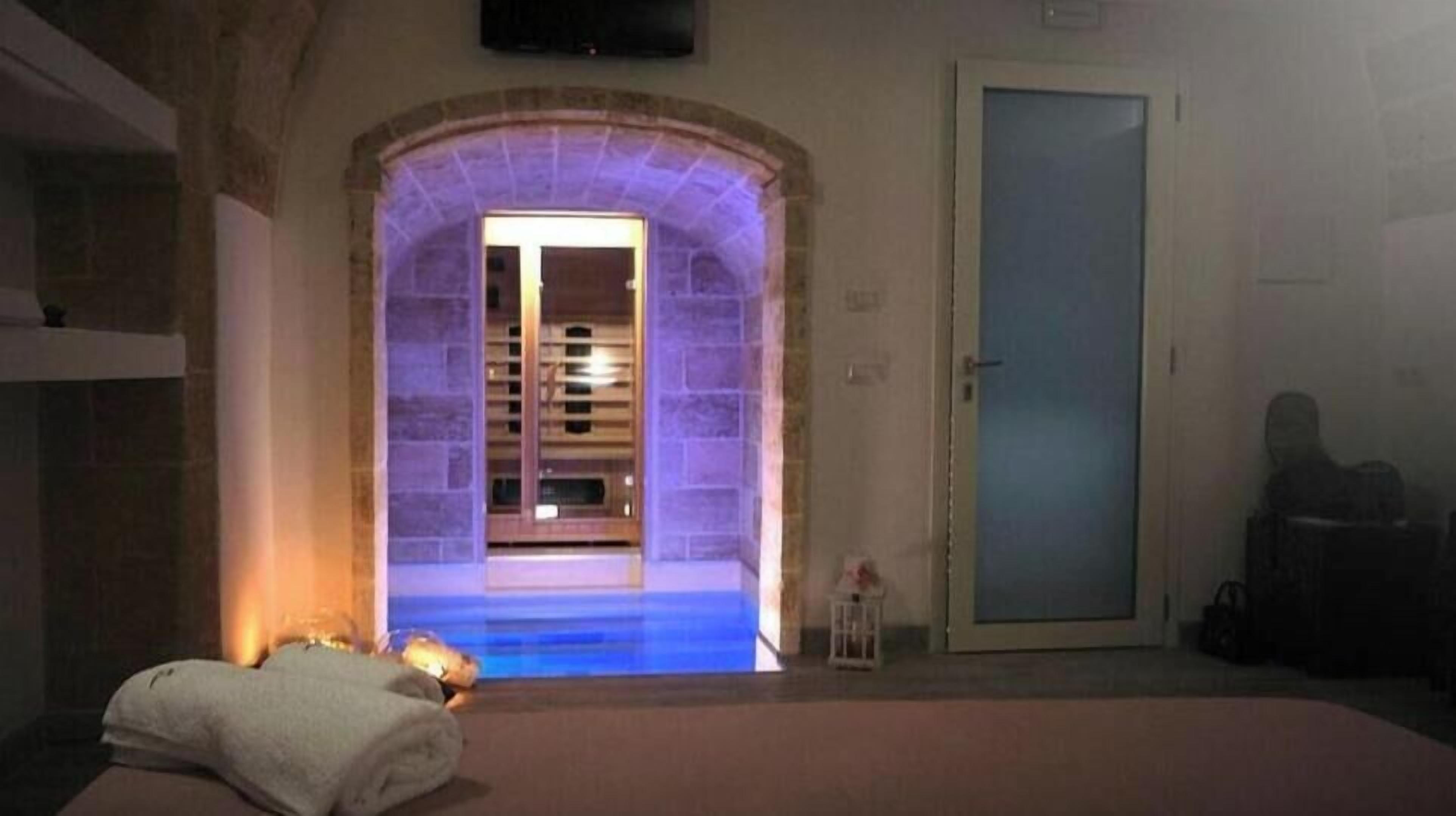 Una habitación con un arco de piedra que da a un baño, una cama con una toalla blanca y una puerta a la derecha.