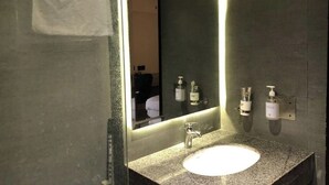 A bathroom with a large mirror, a sink, and two soap dispensers on the wall. - Hamsun Clifton Apartment 3 Bedroom (Karachi)