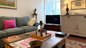 Uma sala de estar com sofá, mesa de centro, televisão, armário e um quadro na parede.
