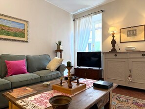 Ein Wohnzimmer mit Sofa, Couchtisch, Fernseher, Schrank und einem Gemälde an der Wand.