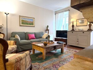 Ein Wohnzimmer mit Sofa, Sessel, Couchtisch, Fernseher und Schrank.