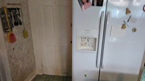 A kitchen with a refrigerator, a tiled floor, and a door. - Charming house in soothing Beckley with cool AC breeze (Beckley)