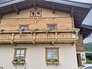 Ein traditionelles Holzhaus mit vielen Fenstern, von denen einige mit Blumenkästen geschmückt sind, und einem Schild, das ein privates Zimmer anzeigt.
