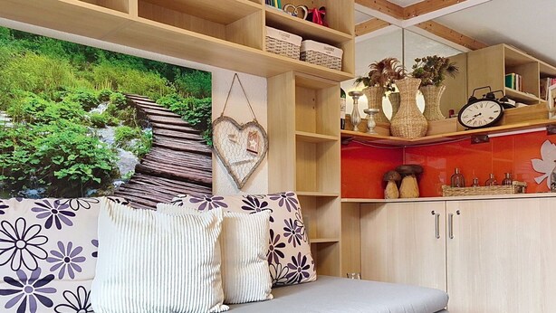 Een woonkamer met een bank, een boekenkast, een aan de muur bevestigd horloge en een decoratieve wandversiering.