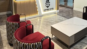 Un comptoir d’accueil orné d’une carte du monde, un lustre moderne et un fauteuil rouge recouvert de tissu.