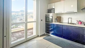 Cocina con vistas a través de un ventanal corredero, microondas, horno y fregadero.