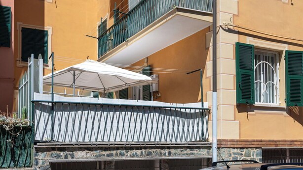 Un edificio de varios pisos con balcones, una sombrilla blanca y una base de piedra.