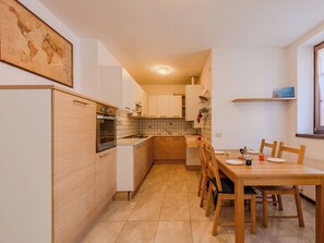 Eine moderne Küche mit Essbereich, ausgestattet mit Herd, Backofen und einer gefliesten Spritzschutzwand.
