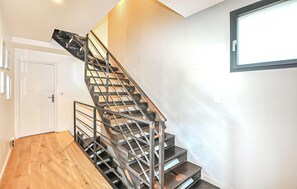 Eine moderne Treppe mit Metallgeländern, Holzboden und einer weißen Tür.