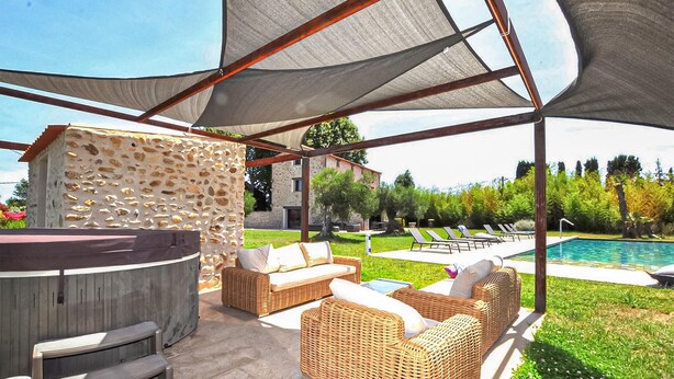 Eine Terrasse im Freien mit Korbmöbeln, einer Steinmauer und einem Pool.