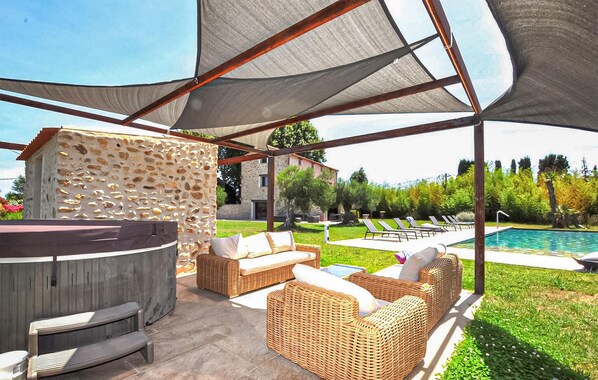 Eine Terrasse im Freien mit Korbmöbeln, einer Steinwand und einem Pool.