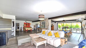 Ein modernes Wohnzimmer mit einer Couch, einem Hocker und einem Essbereich mit Stühlen.