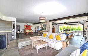 Ein modernes Wohnzimmer mit einer Couch, einem Hocker und einem Essbereich mit Stühlen.