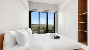 A bedroom with a large bed, a view of the countryside through a window, and a wardrobe. - Free Housekeeping Visits During Your Stay - Stayshort - Studio in Dubai Land That Sleeps 3 Close to Global Village (Dubai)