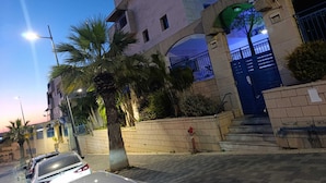 A multi-story building with a blue gate, palm trees, and a streetlight. - Luxury Stunning 2BR Marina Apt with Sea View (Ashkelon)