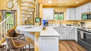L’intérieur d’une cabane en bois comprend une cuisine, un coin repas et un escalier.