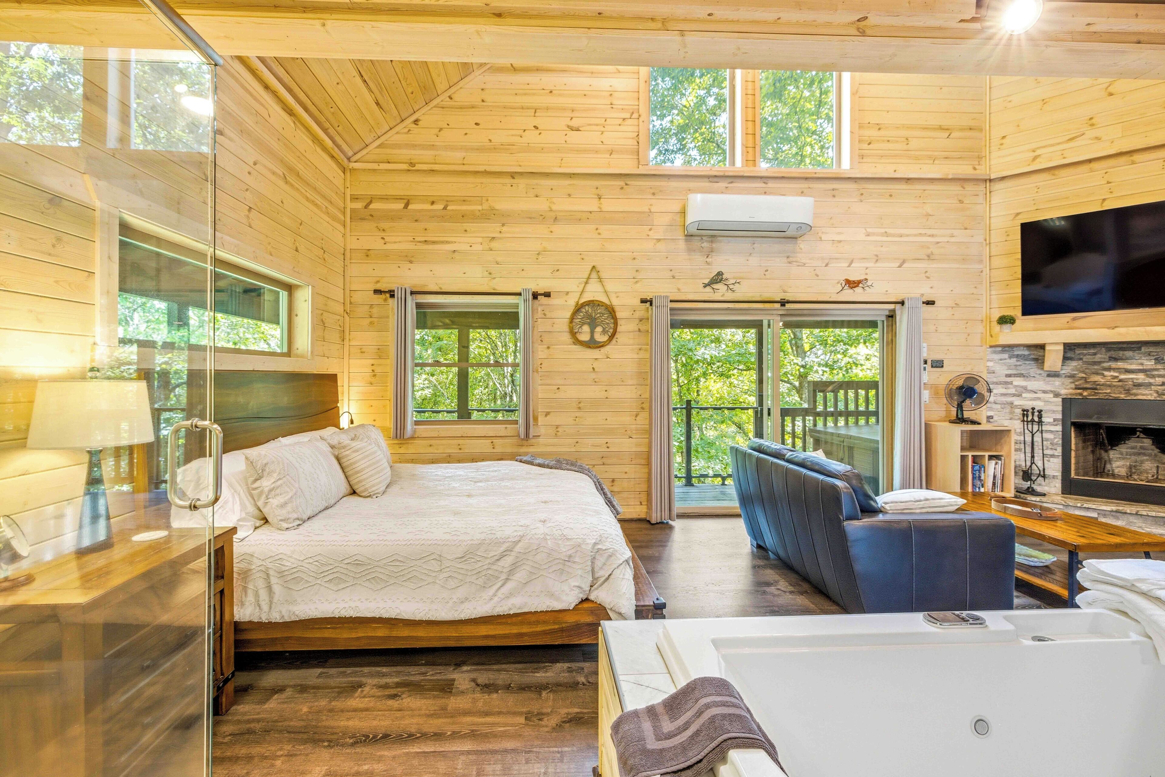 Ein rustikales Holzhütten-Interieur mit Bett, Sofa, Badewanne und Kamin.