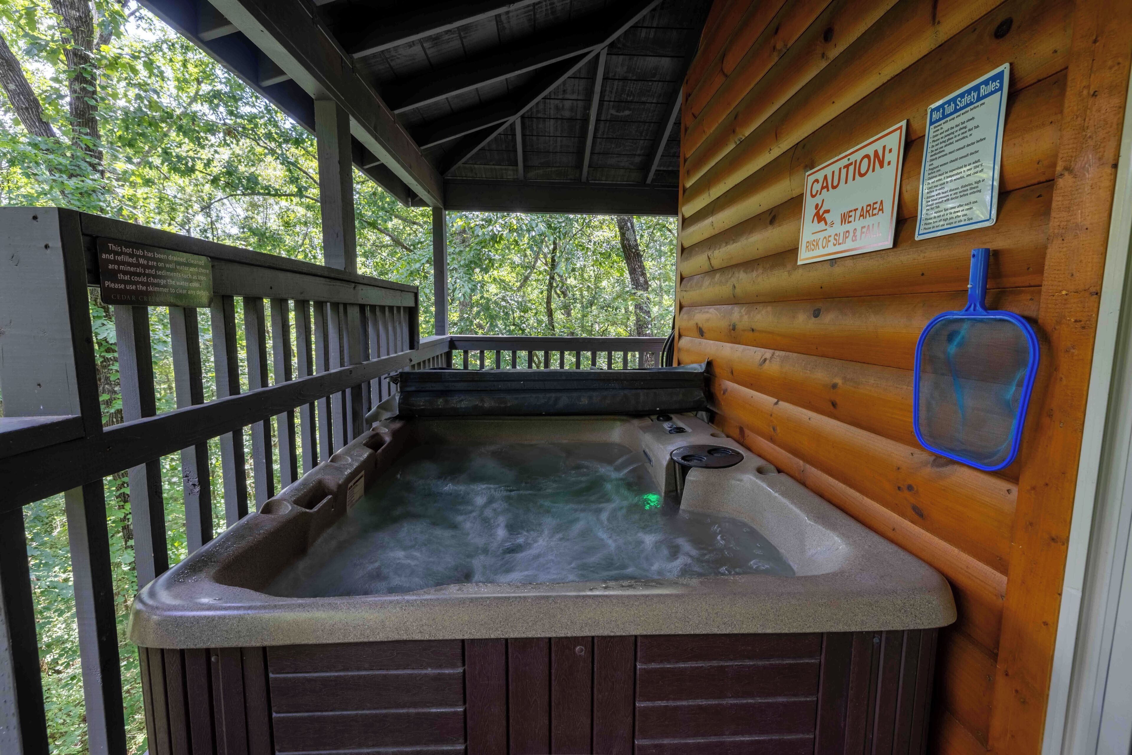 Ein Whirlpool mit einer Holzterrasse und einem Warnschild wegen Nässe.
