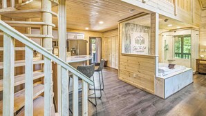 L’intérieur d’une cabane en bois comprend un escalier en colimaçon, un coin cuisine et une salle de bain avec une douche en verre.