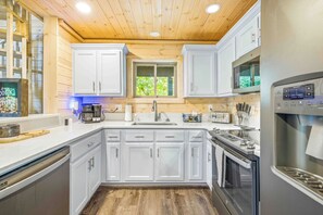 A modern kitchen with white cabinets, a stainless steel range, and a built-in microwave. - Sky's the Limit - Make a Wish Come True and Book a Treehouse (Cleveland)