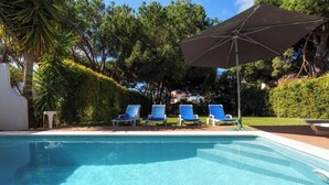 Ein Swimmingpool mit Liegestühlen und einem Sonnenschirm.