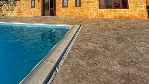 Un edificio de piedra con piscina, que cuenta con un amplio ventanal de arco y una puerta pequeña.