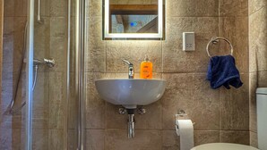 Un baño con cabina de ducha de vidrio, un lavabo con espejo y un inodoro.
