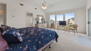 Ein Schlafzimmer mit einem Bett, einem Deckenventilator, einem Schreibtisch mit Stuhl und einem Fernseher.