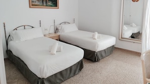 Ein Doppelzimmer mit zwei Betten, einem Nachttisch, einer Lampe, einem Gemälde, einem Spiegel und einer gewobenen Leuchte.