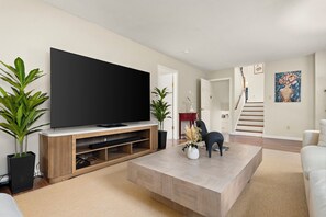 Un salon moderne doté d’un téléviseur à écran plat, d’un meuble de rangement en bois, d’une table basse et d’un escalier menant à un autre niveau.