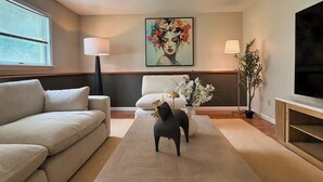 Una sala de estar moderna con un sofá, una mesa de centro, un televisor y un cuadro en la pared.