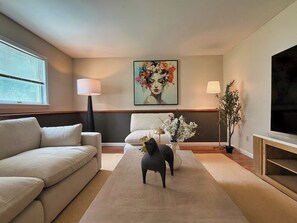 Ein modernes Wohnzimmer mit einer Couch, einem Couchtisch, einem Fernseher und einem Gemälde an der Wand.