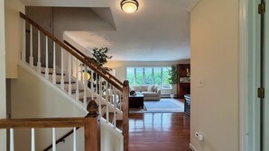 Una escalera conduce a un área de estar con un sofá y un ventanal.