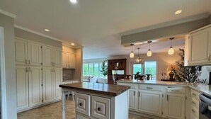 Una cocina amplia con armarios blancos, una isla central e iluminación colgante.