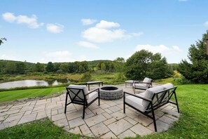 Une terrasse extérieure avec un sol en pierre, un foyer et du mobilier d’extérieur.