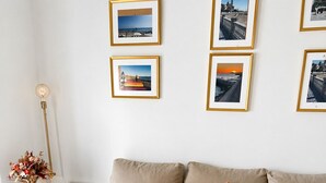 Una sala de estar moderna con un sofá color beige, una mesa de centro de vidrio y cuadros en la pared.