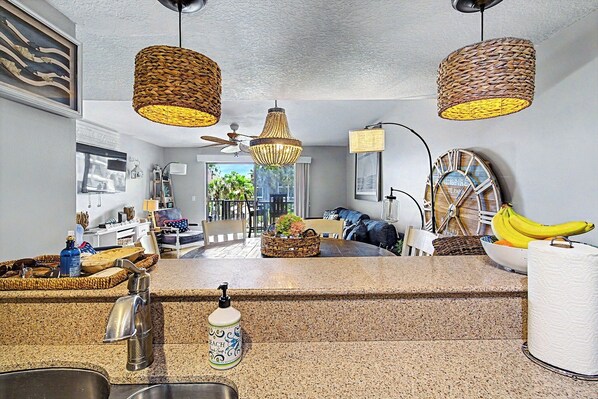 A kitchen with granite countertops, a ceiling fan, and a view of the living area. - New Listing! Townhouse Style Condo With Ocean And Pool Views. (Saint Augustine)