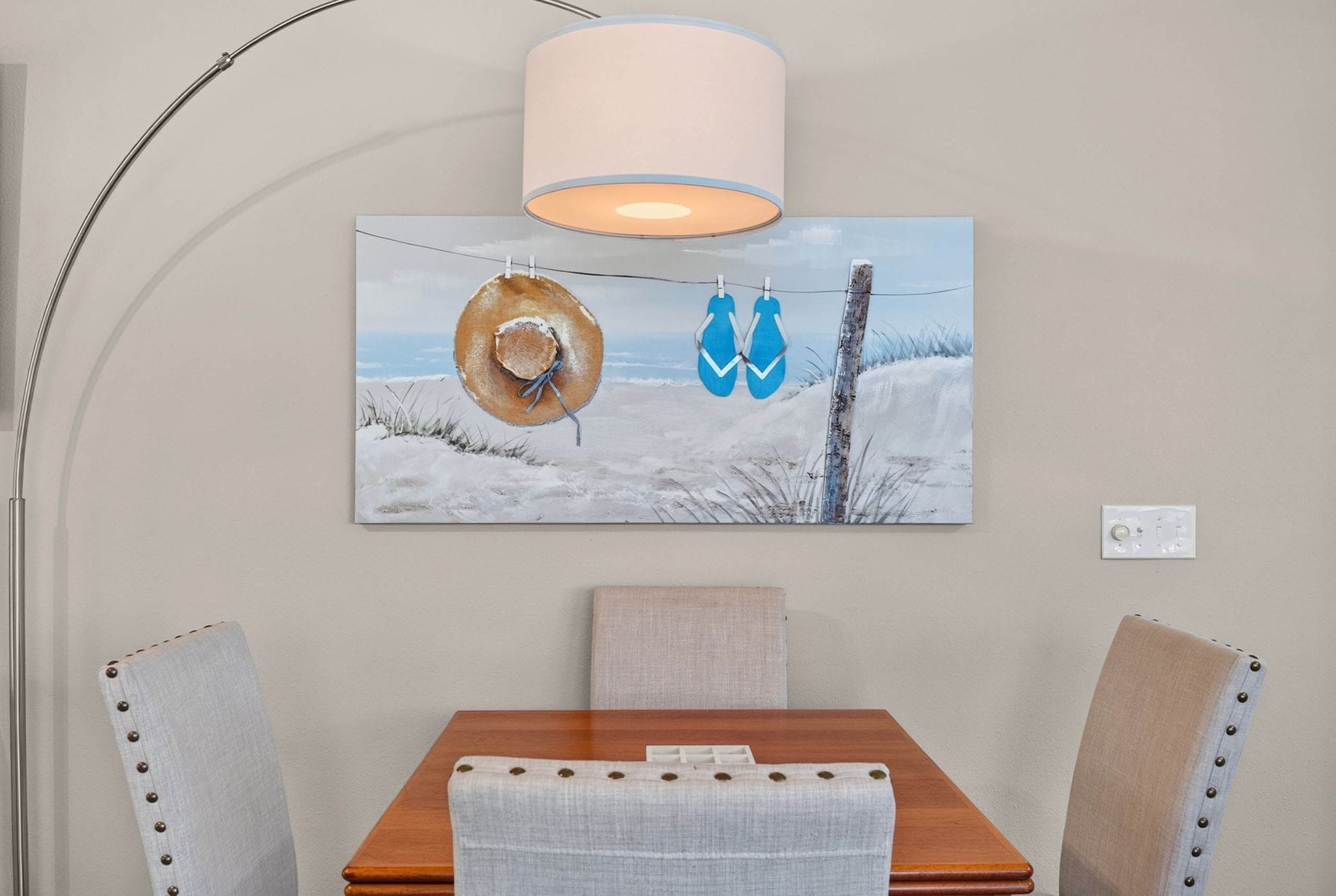 A dining area with a table, chairs, a lamp, and a wall-mounted painting.