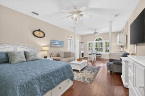 A spacious bedroom with a large bed, a sitting area with a sofa, and a desk. - Easy Breezy on the 16th Green in Sunset Beach (Sunset Beach)